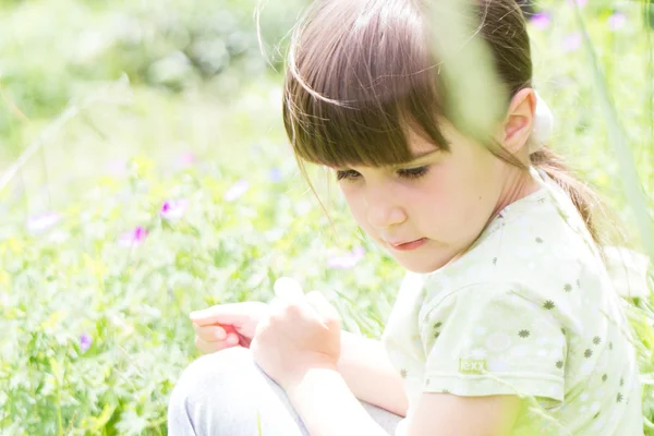 Dziewczynka siedzi w trawie — Zdjęcie stockowe
