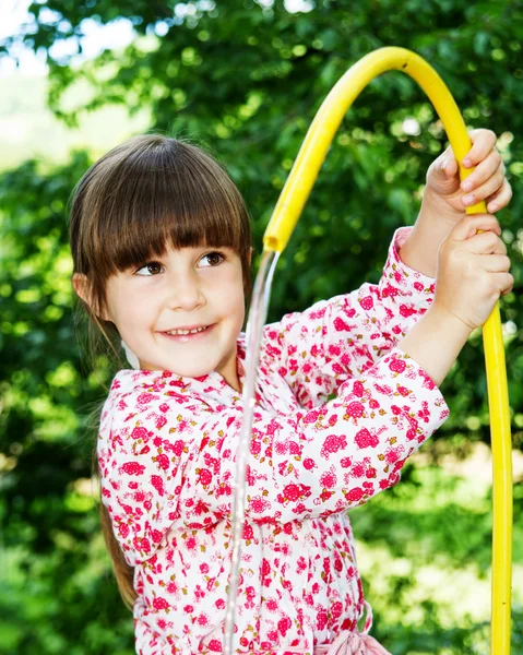 Klein meisje spelen met slang en water — Stockfoto