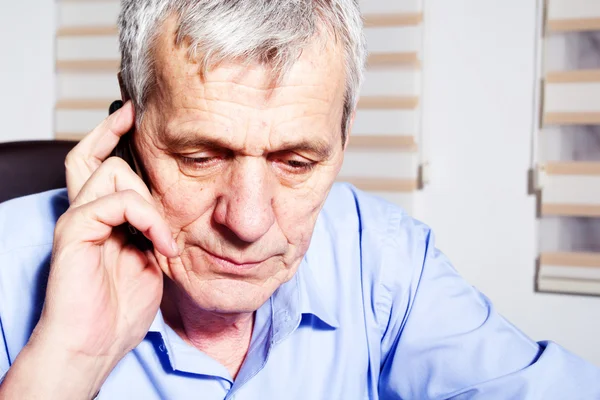 Um empresário sênior usando o telefone em seu escritório — Fotografia de Stock