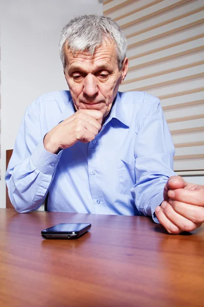 Een senior zakenman met behulp van telefoon op zijn kantoor — Stockfoto
