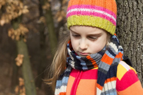 Sad little girl in the autumn park — Stock Photo, Image