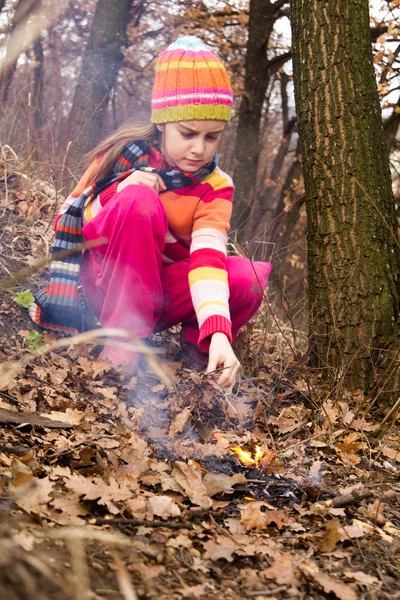 Bambina che accende il fuoco nella foresta - gioco pericoloso — Foto Stock