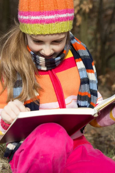 Lilla asiatiska barn läser en bok utomhus — Stockfoto