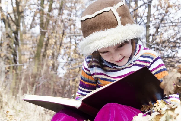 Aziatische kindje lezen van een boek buiten — Stockfoto