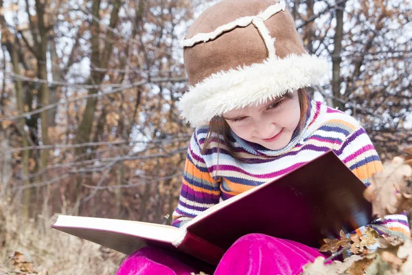 Kleines asiatisches Kind liest draußen ein Buch — Stockfoto