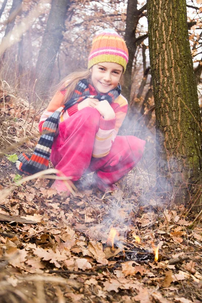 Little girl lighting fire in forest - dangerous playing — Stock Photo, Image
