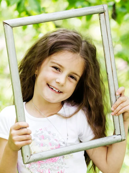 Kleines Mädchen sucht Holzrahmen - schöne Natur-Rückseite — Stockfoto