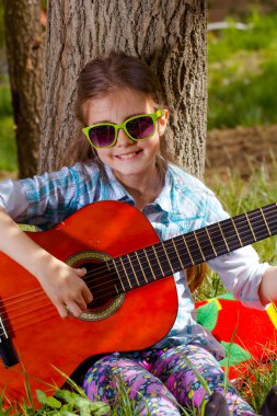 sevimli küçük kız bir gitar çalmak. bahar zamanı