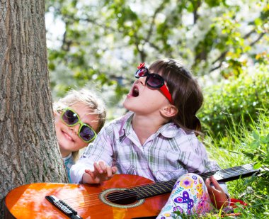bir eğlence ve bir gitar açık oynayan iki küçük kız var