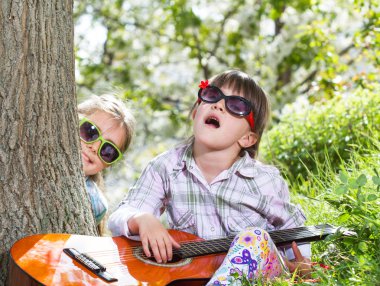 bir eğlence ve bir gitar açık oynayan iki küçük kız var
