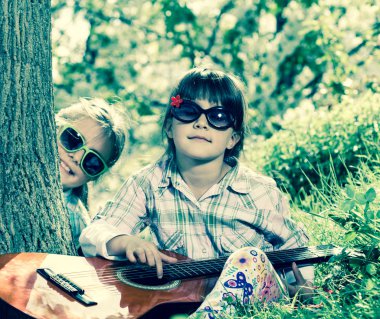 bir eğlence ve bir gitar açık oynayan iki küçük kız var