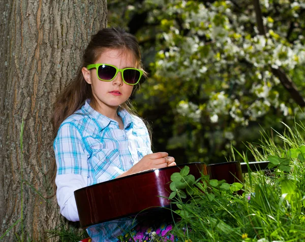 Söt liten flicka spela gitarr. våren — Stockfoto