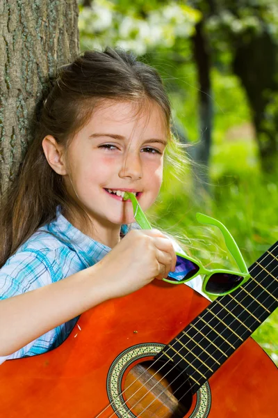 Hübsches kleines Mädchen, das Gitarre spielt. Frühlingszeit — Stockfoto