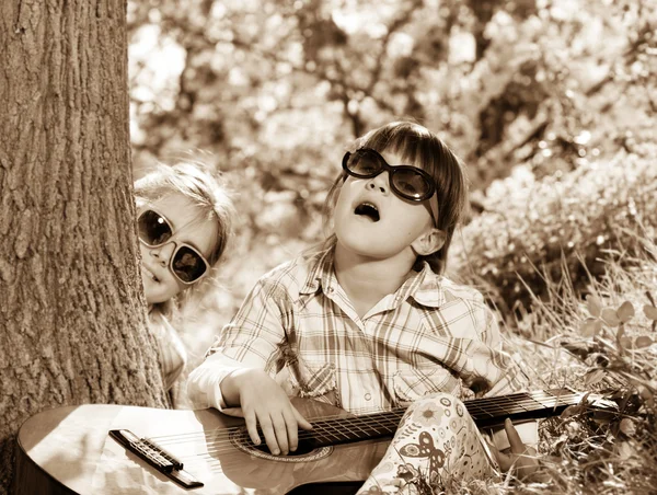 Zwei kleine Mädchen haben Spaß und spielen eine Gitarre im Freien — Stockfoto