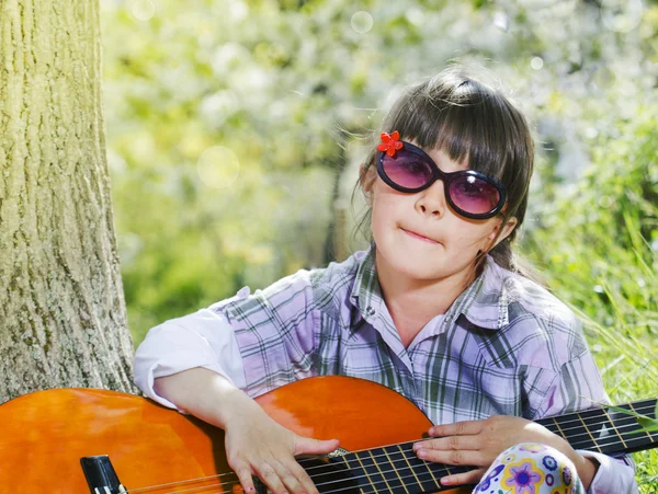 Gelukkig meisje met glazen gitaarspelen buiten — Stockfoto