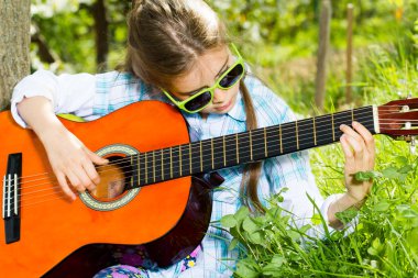 sevimli küçük kız bir gitar çalmak. bahar zamanı