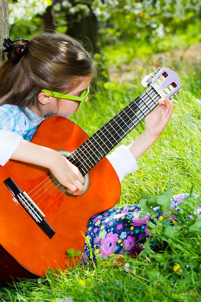 Pretty little girl playing a guitar. Spring time — Stock Photo, Image
