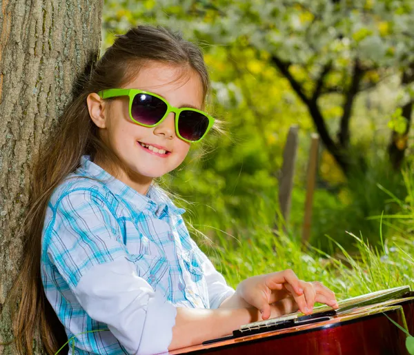 Sevimli küçük kız bir gitar çalmak. bahar zamanı — Stok fotoğraf