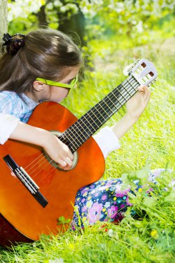 sevimli küçük kız bir gitar çalmak. bahar zamanı