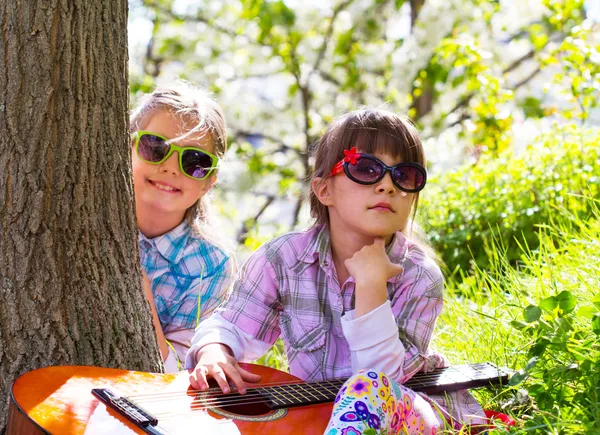 Zwei kleine Mädchen haben Spaß und spielen eine Gitarre im Freien — Stockfoto