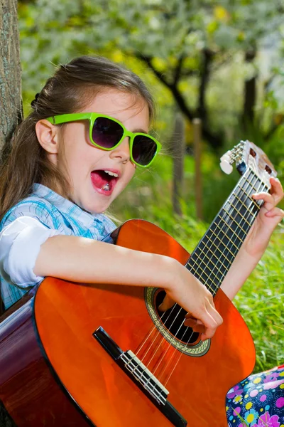Hübsches kleines Mädchen, das Gitarre spielt. Frühlingszeit — Stockfoto