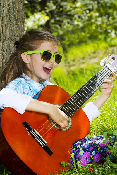 Hübsches kleines Mädchen, das Gitarre spielt. Frühlingszeit — Stockfoto