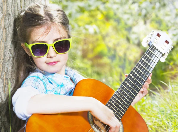 Hübsches kleines Mädchen, das Gitarre spielt. Frühlingszeit — Stockfoto