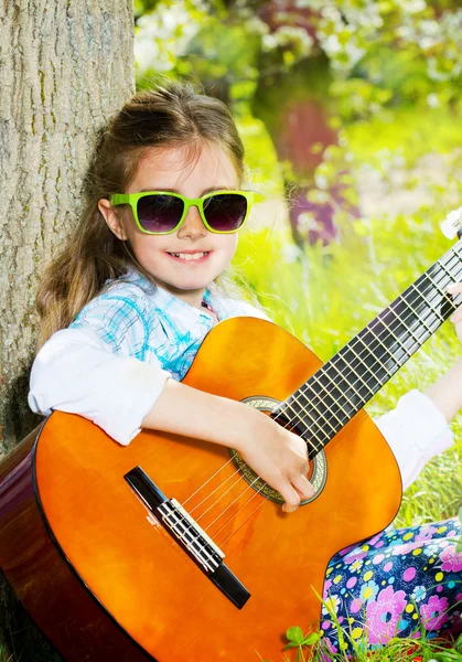 Sevimli küçük kız bir gitar çalmak. bahar zamanı — Stok fotoğraf