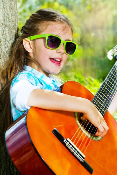 Hübsches kleines Mädchen, das Gitarre spielt. Frühlingszeit — Stockfoto