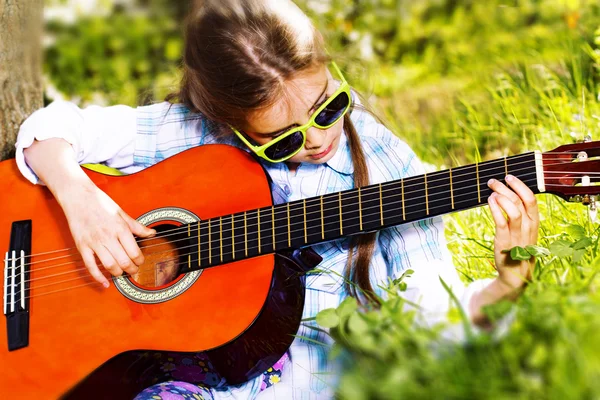 Całkiem mała dziewczynka gra na gitarze. wiosną — Zdjęcie stockowe