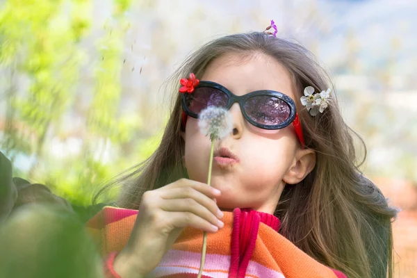 Weinig meisje waait paardebloem — Stockfoto