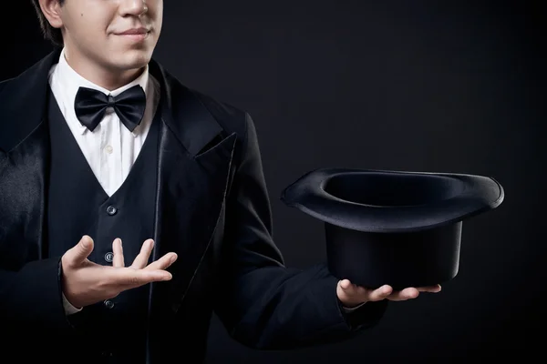 Closeup of magician showing tricks with top hat isolated on dark background — Stock Photo, Image