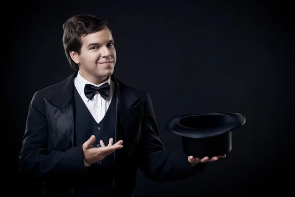 Mago mostrando trucos con sombrero de copa aislado sobre fondo oscuro — Foto de Stock