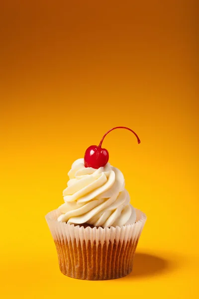 Cupcake met rode kers geïsoleerd op oranje achtergrond met werkrug — Stockfoto