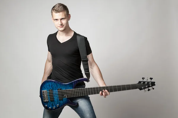 young male musician with six-string bass guitar isolated on ligh
