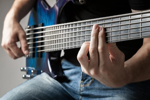 Músico masculino tocando na guitarra baixo de seis cordas — Fotografia de Stock