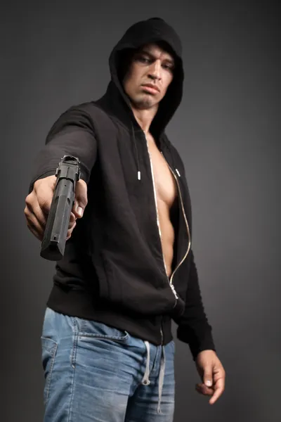 Hombre disparando arma aislada sobre fondo gris. enfoque en el arma — Foto de Stock