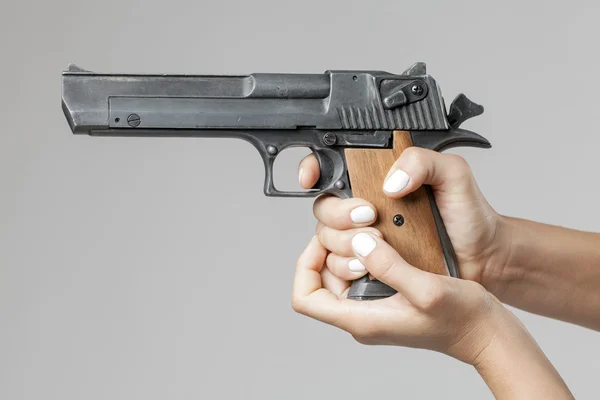 灰色の背景で隔離の銃を持つ女性の手 — ストック写真
