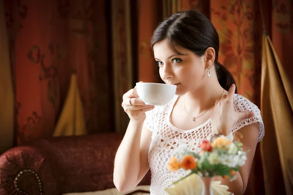 Elegante vrouw met een mok thee in café — Stockfoto