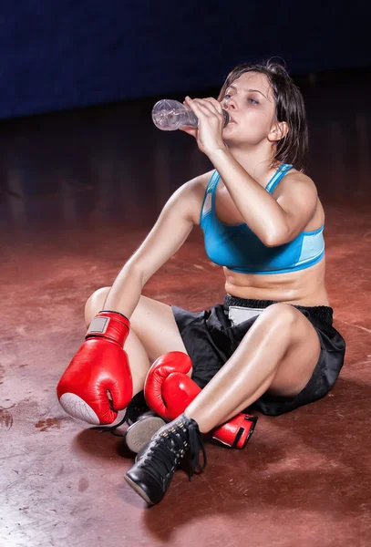 A menina boxeador sentado em um chão em um salão depois de trem cansativo — Fotografia de Stock