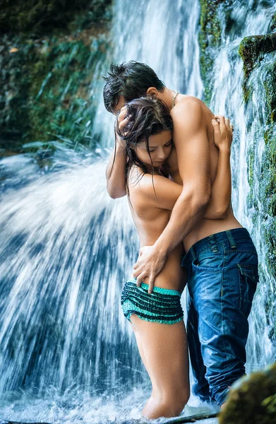 Pareja abrazándose y besándose bajo cascada — Foto de Stock