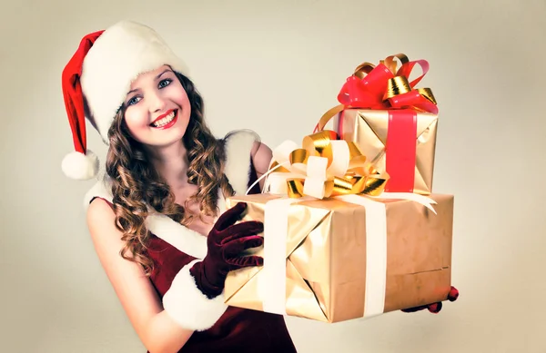 Hermosa mujer en un vestido rojo y sombrero de Santa con un gran regalo —  Fotos de Stock