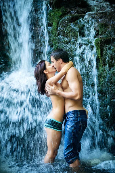 Pareja abrazándose y besándose bajo cascada — Foto de Stock