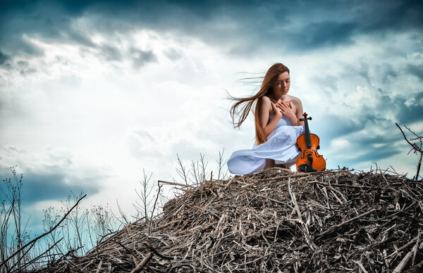 Рыжая девушка со скрипкой на открытом воздухе
