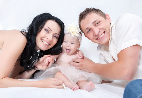 Egy boldog család a fehér ágyon a hálószobában — Stock Fotó