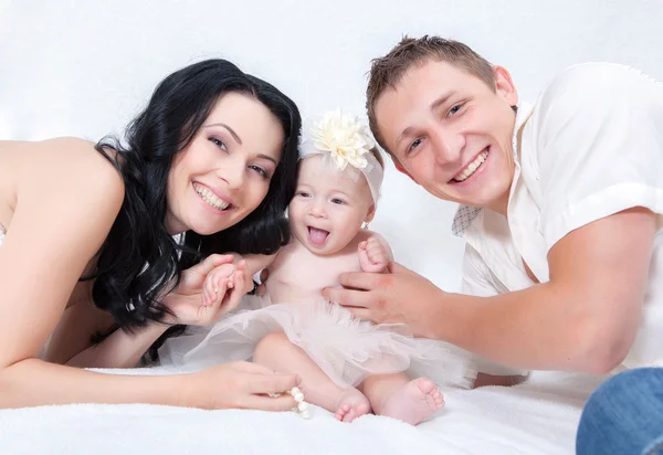 Uma família feliz na cama branca no quarto — Fotografia de Stock