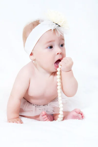 Pasgeboren baby portret zittend op een bed met een parel ketting — Stockfoto