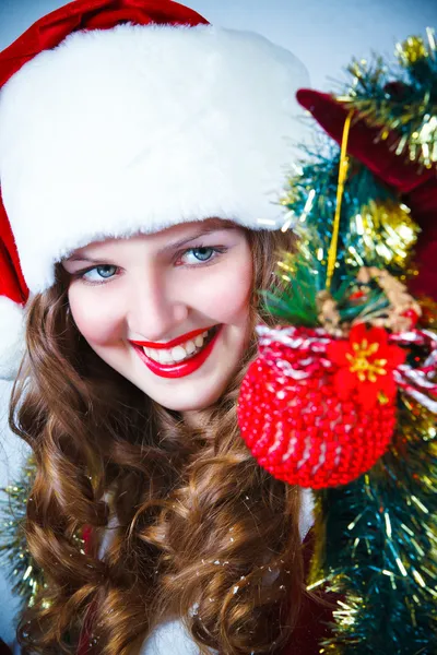 Hermosa mujer en un vestido rojo y sombrero de Santa con una Navidad —  Fotos de Stock