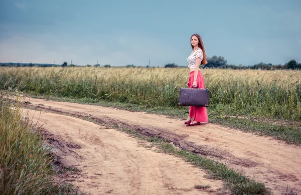 Dívka s starý kufr na silnici — Stock fotografie