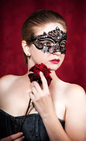 Karnaval maskesi kırmızı gül ile güzel bir kadın portresi — Stok fotoğraf